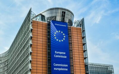 Façade de la Commission européenne à Bruxelles avec une grande banderole qui pend, bleue, et les mots Commission européenne écrit en plusieurs langues.